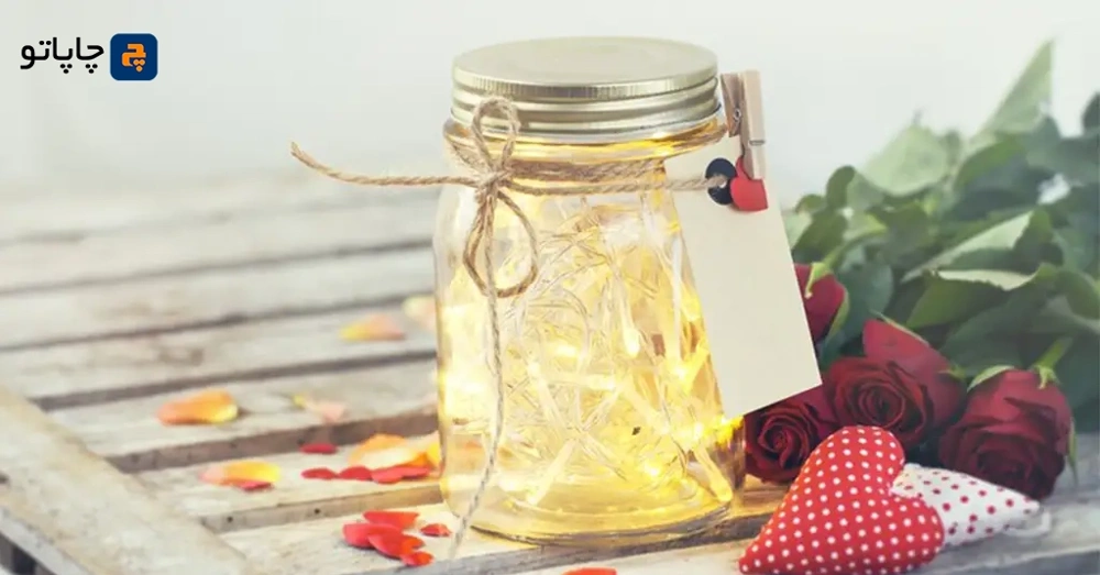بطری شیشه ای با ریسه نوری طلایی داخل آن، بعنوان ایده بسته بندی هدیه ولنتاین